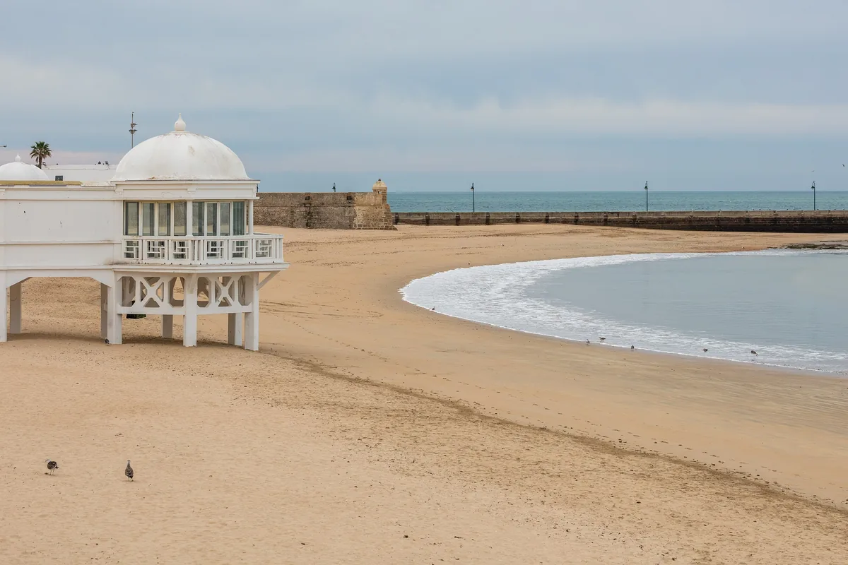 The beach of La Caleta in Cádiz with the old bathing pavilion and boats