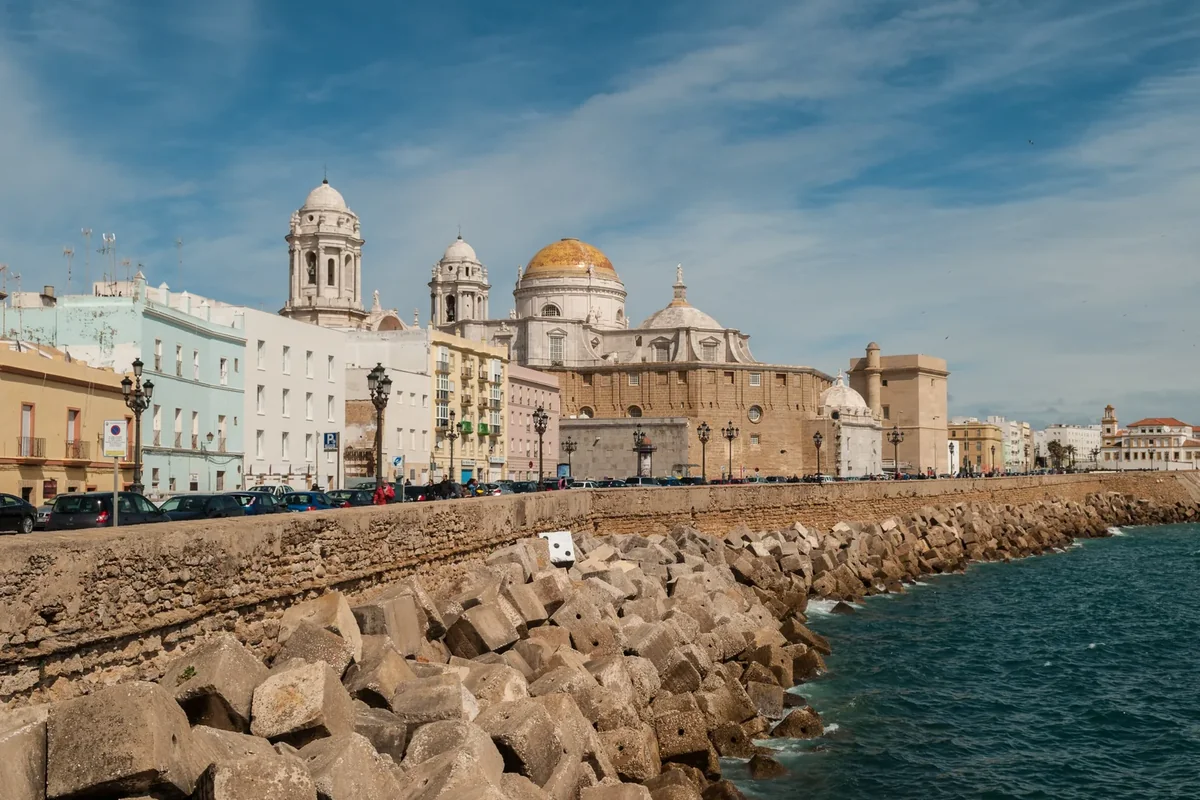 The seafront of Cádiz with the cathedral dome above white buildings and the sea