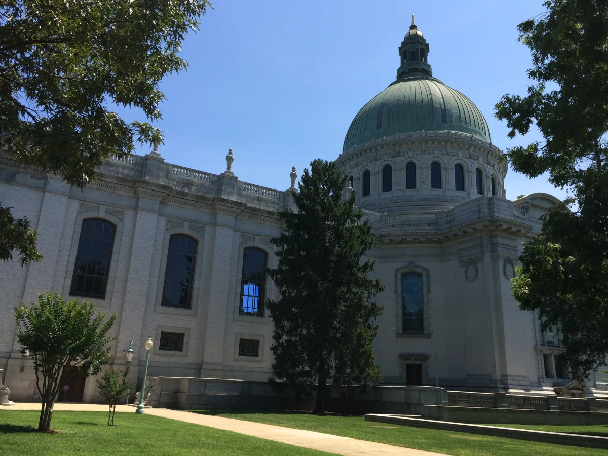 The Naval Academy Chapel with its large green copper dome behind trees and a lawn