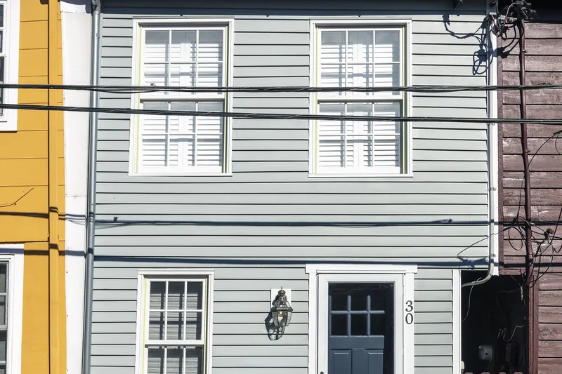 A narrow gray clapboard row house with a red roof on Fleet Street in Annapolis