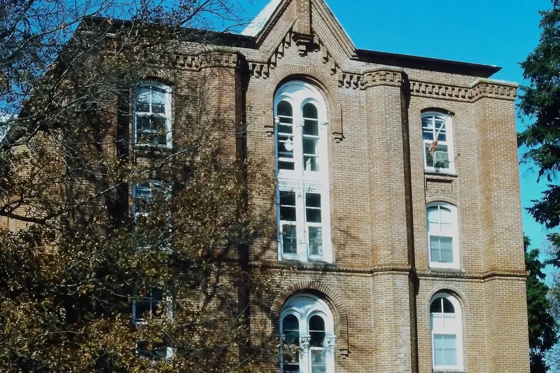 A brick Romanesque Revival hall at St. John’s College with tall arched windows