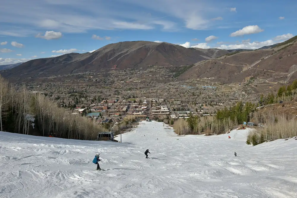 Skiers on Aspen Mountain with the town of Aspen below