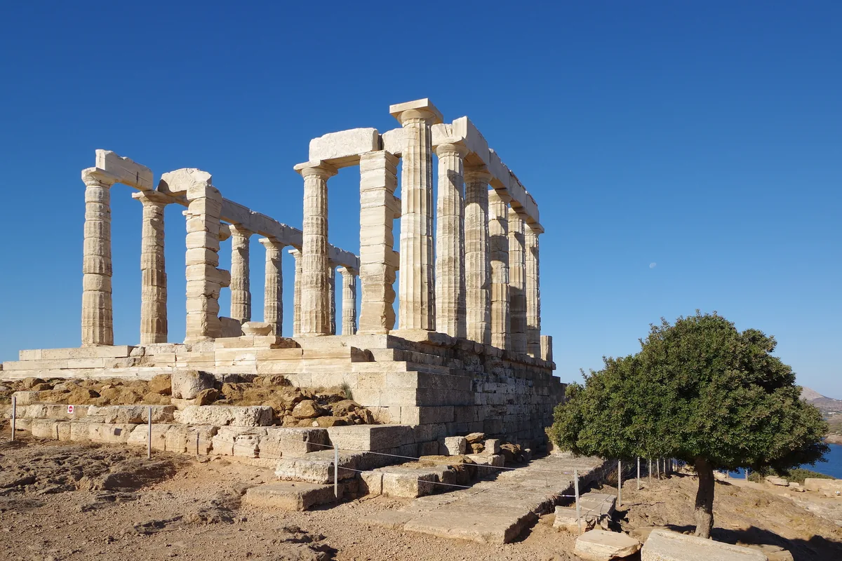 The columns of the Temple of Poseidon on Cape Sounion beside a pine tree