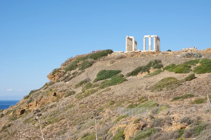 The Temple of Poseidon on top of the scrubby headland of Cape Sounion above the sea