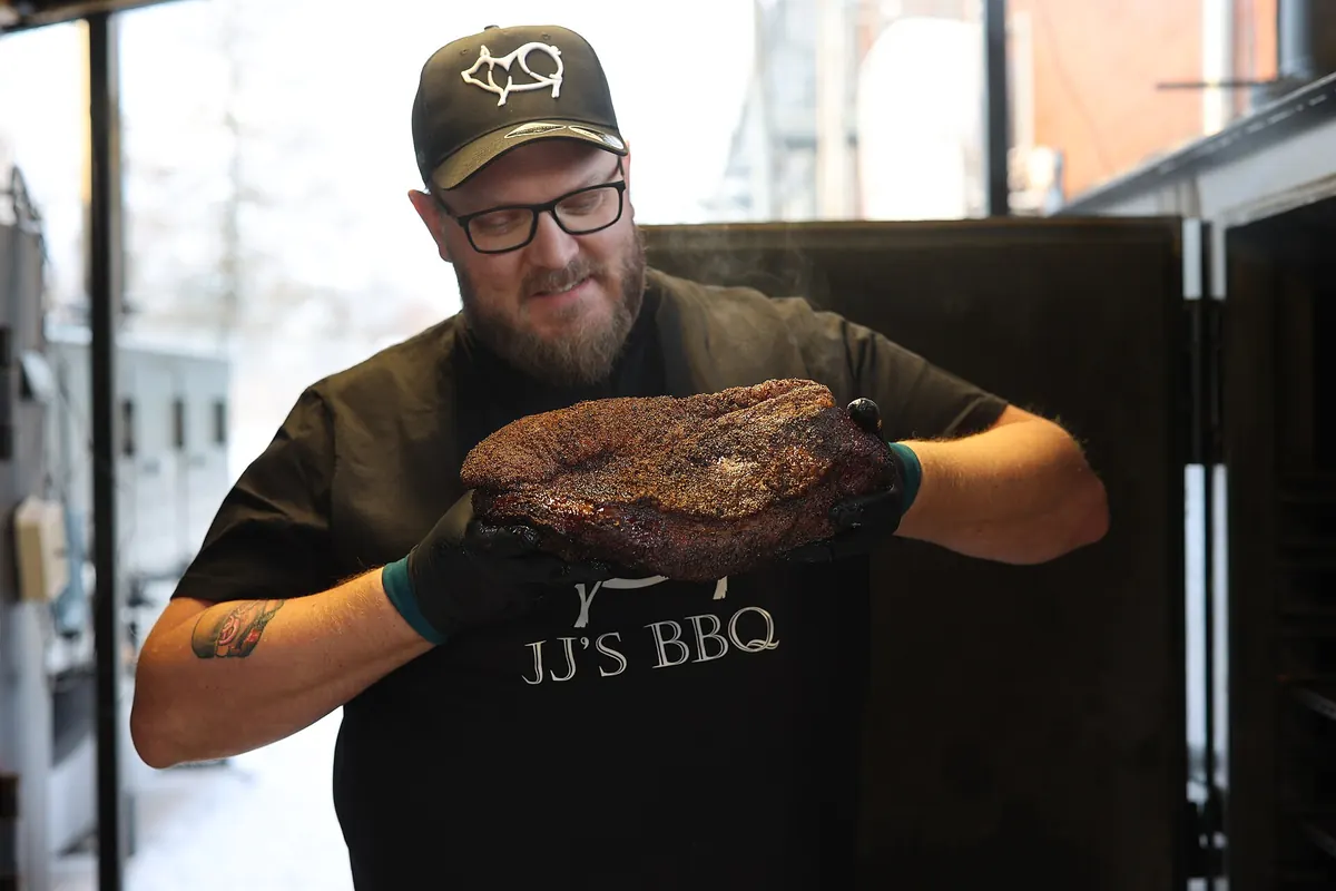 A pitmaster holding a smoked brisket at a Texas barbecue joint