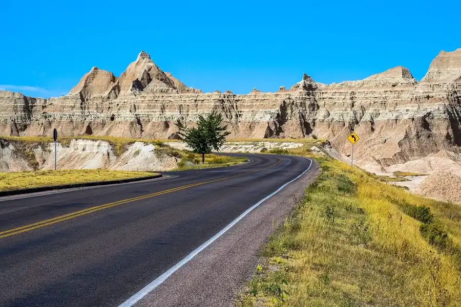 Badlands formations rising over the prairie under a blue sky
