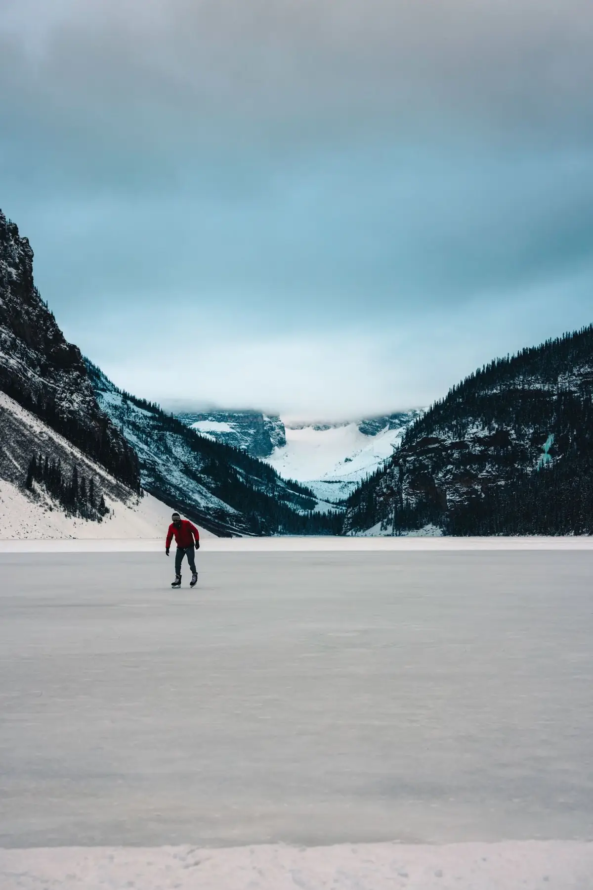 A lone skater on frozen Lake Louise with Victoria Glacier