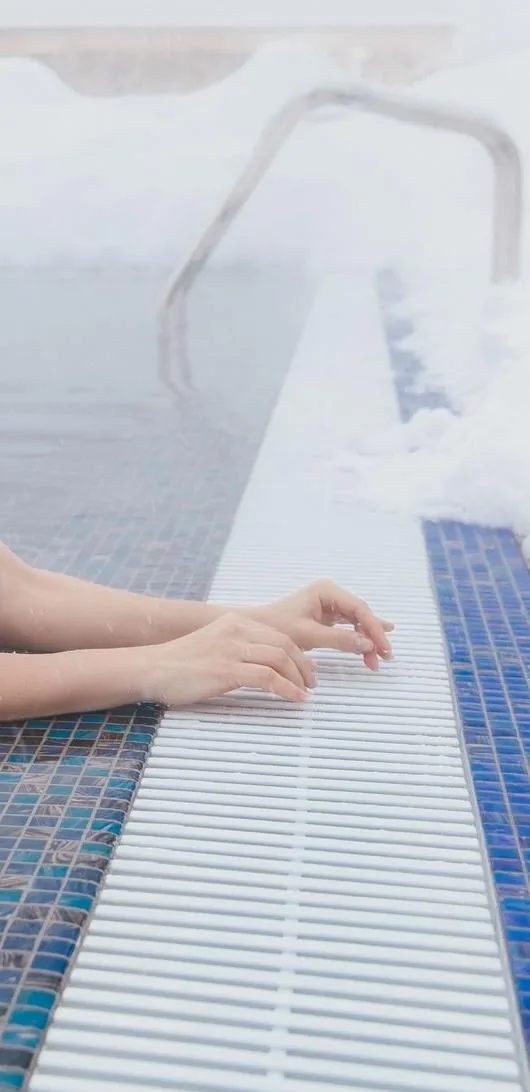Steam rising off an outdoor hot spring pool in winter