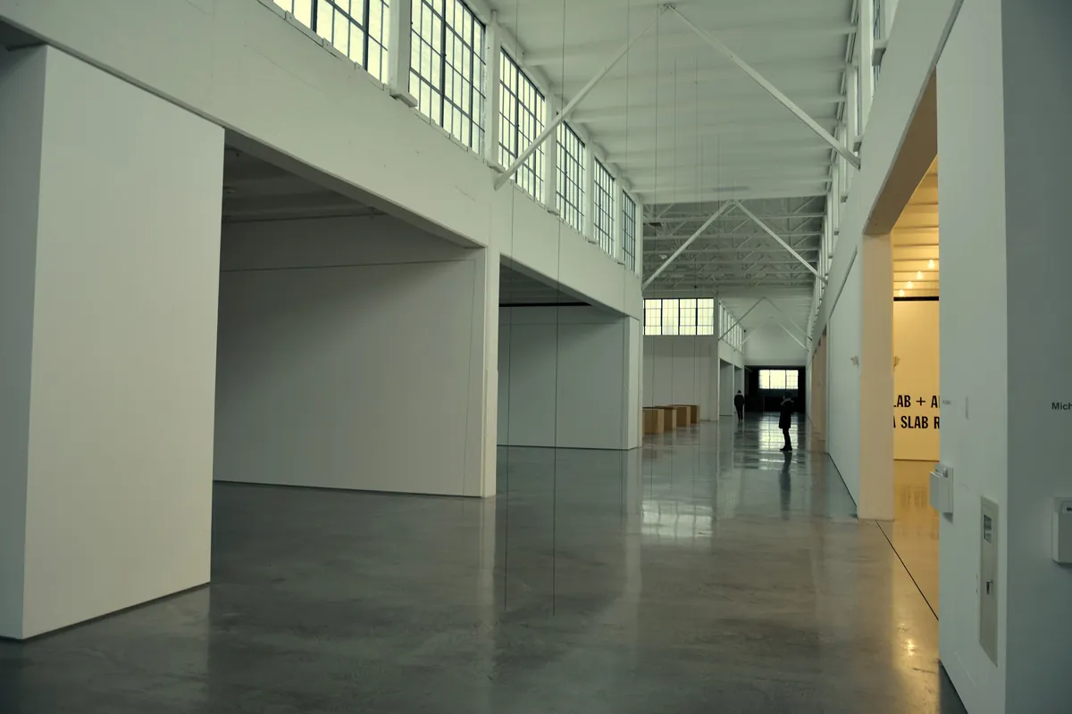 A long white gallery with concrete floors and skylights at Dia Beacon