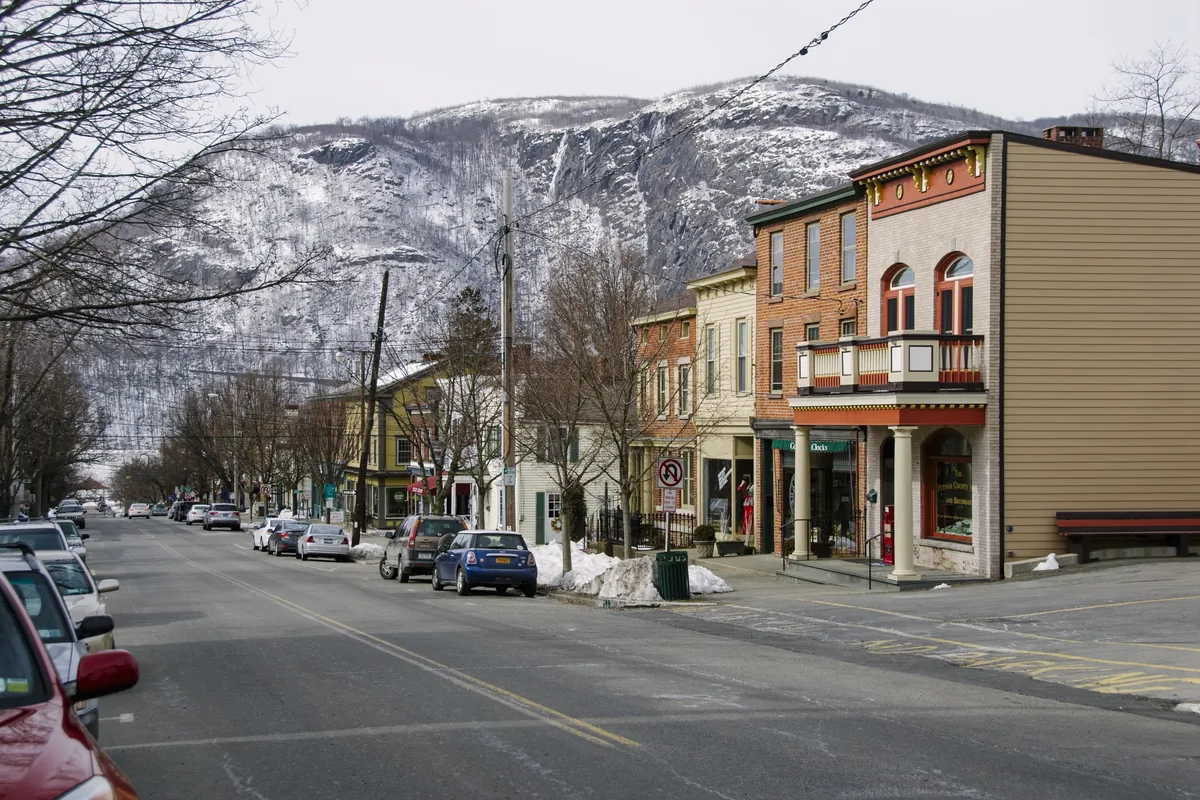 Main Street in Cold Spring in winter with old storefronts and a snowy ridge behind