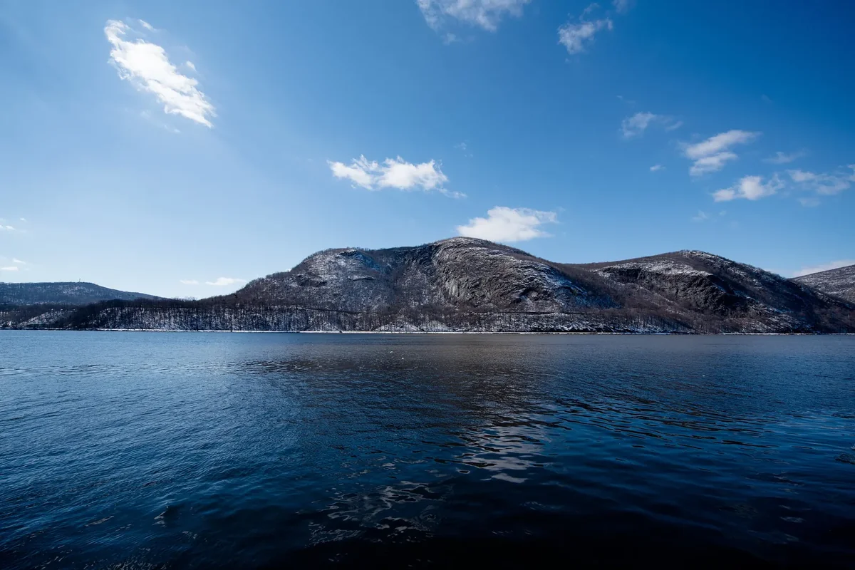 The Hudson River at Cold Spring with Storm King Mountain across the water under a blue sky