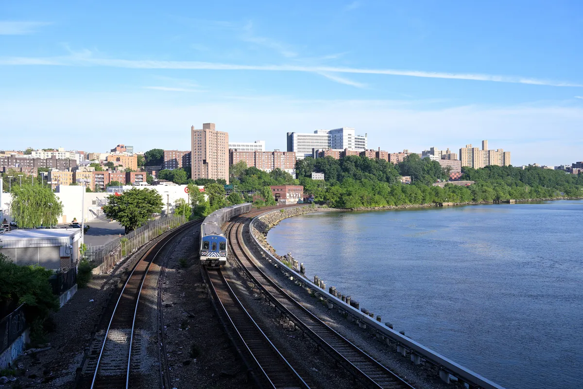 A Metro-North Hudson Line train on tracks beside the Hudson River
