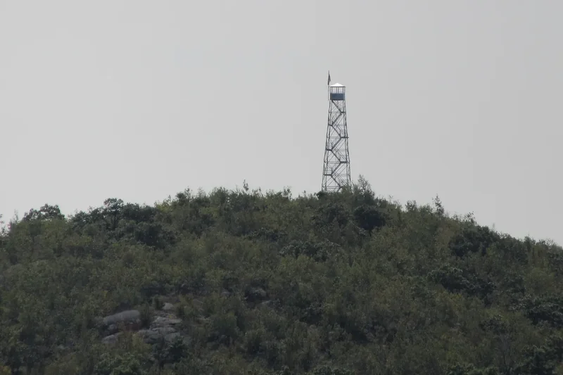 A steel fire lookout tower on the wooded summit of Mount Beacon