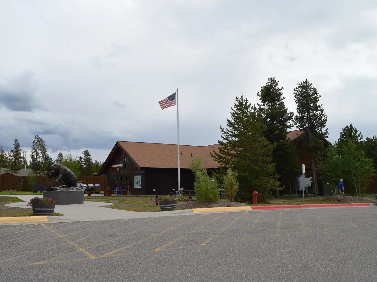 The low timber entrance building of the Grizzly and Wolf Discovery Center in West Yellowstone, with a flagpole and tall pines