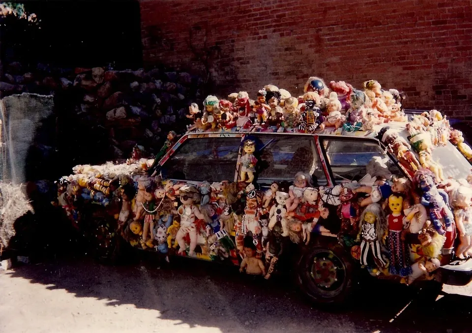 A car covered in dolls parked on a street in Bisbee