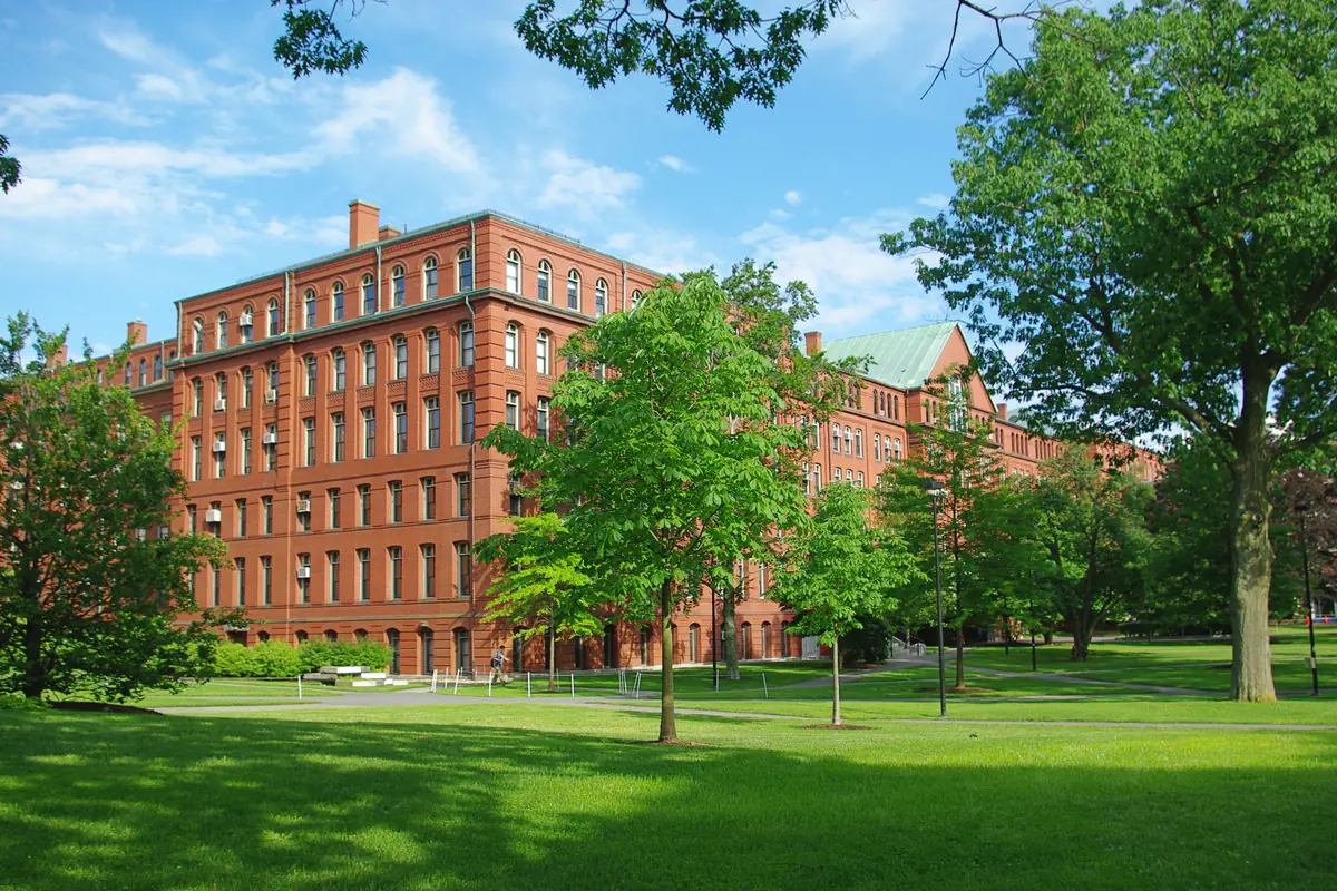 The red-brick Harvard Museum of Natural History building on Oxford Street behind green lawns and trees
