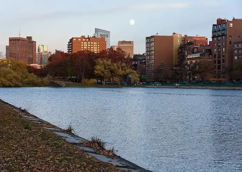 Boston's Back Bay skyline across the Charles River in fall, with the moon rising