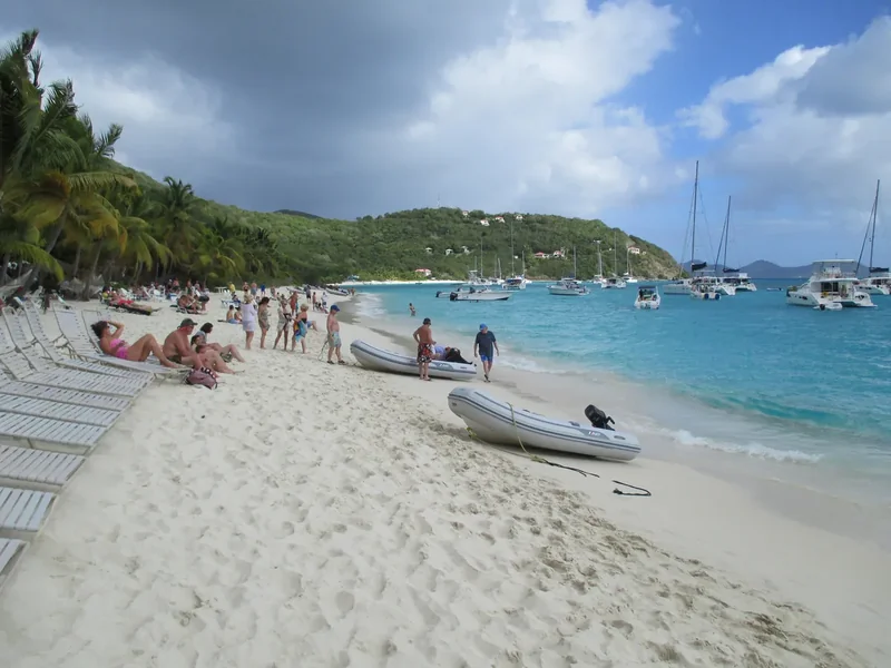 The curved white-sand beach of White Bay on Jost Van Dyke with boats offshore