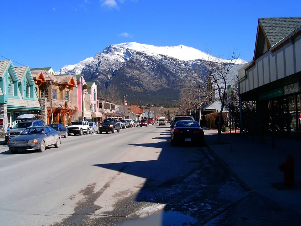 Canmore’s Main Street with low shops and cars, and a snowy mountain at the end of the street