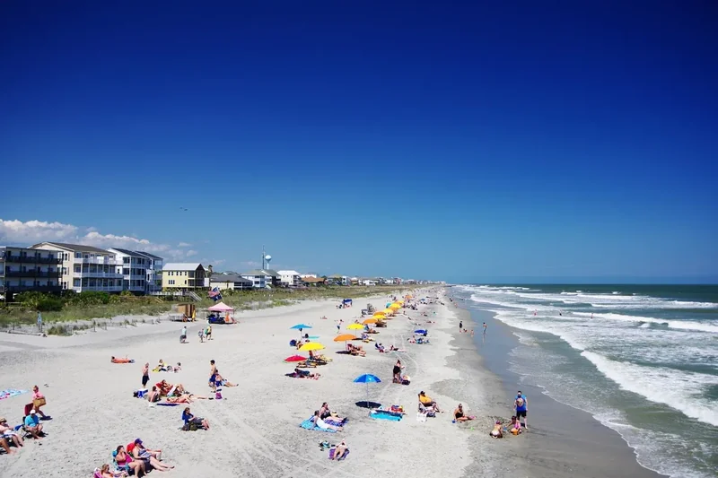 Folly Beach seen from the pier, the shoreline with swimmers and houses behind the dunes