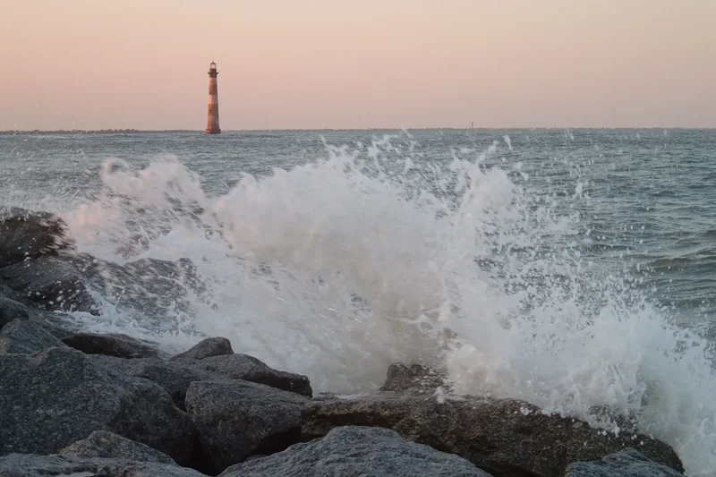The Morris Island Lighthouse standing offshore in the water, seen from Folly Island