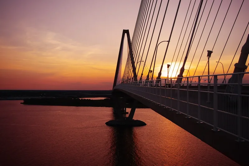 The Arthur Ravenel Jr. Bridge in Charleston at sunset, its cable towers against an orange sky