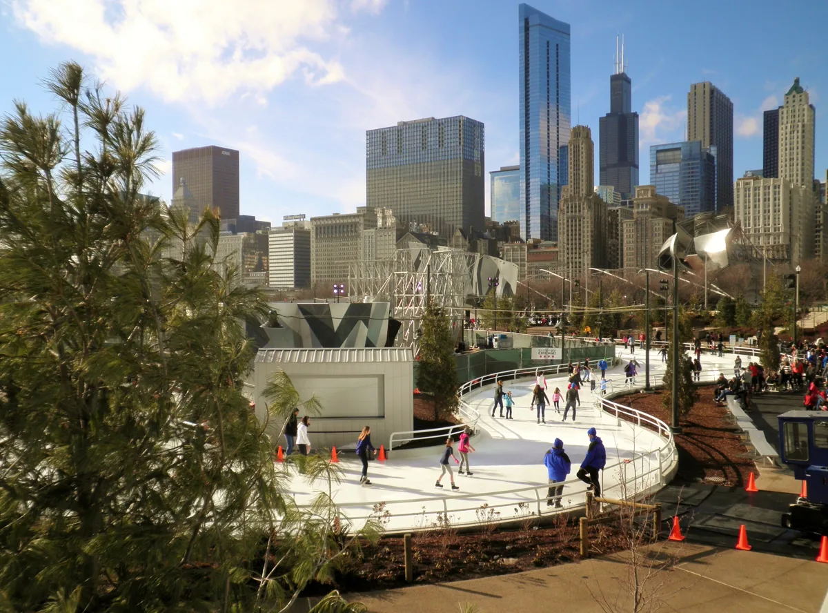 The winding Skating Ribbon at Maggie Daley Park with skaters and the Chicago skyline behind