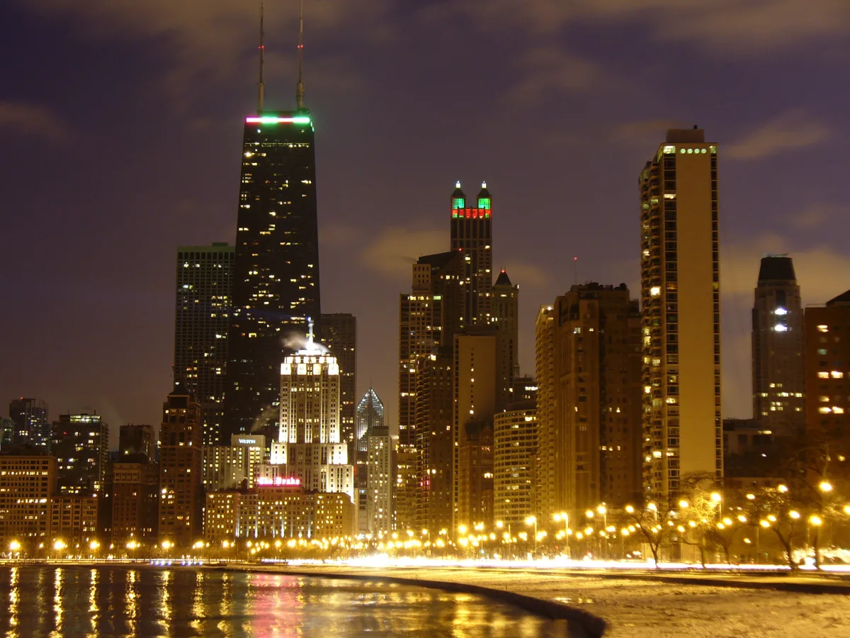 The Chicago skyline lit at night above Oak Street Beach and Lake Shore Drive in winter