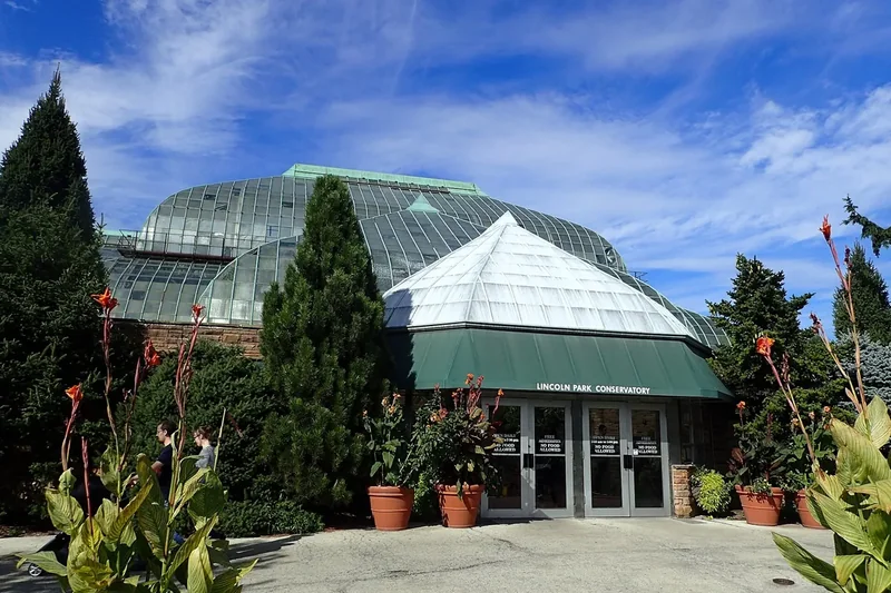 The glass dome and entrance of the Lincoln Park Conservatory among evergreens