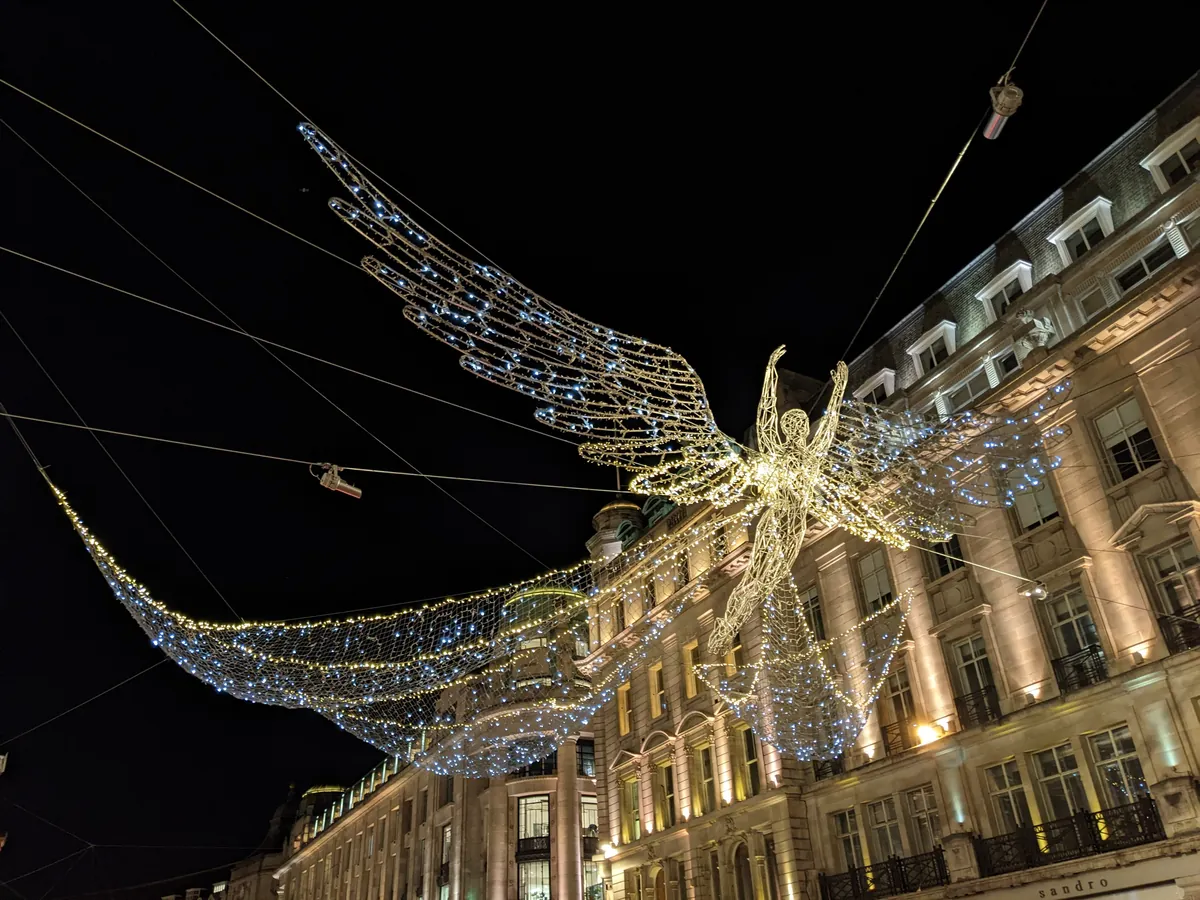 Glowing angel-shaped Christmas lights hanging over Regent Street at night