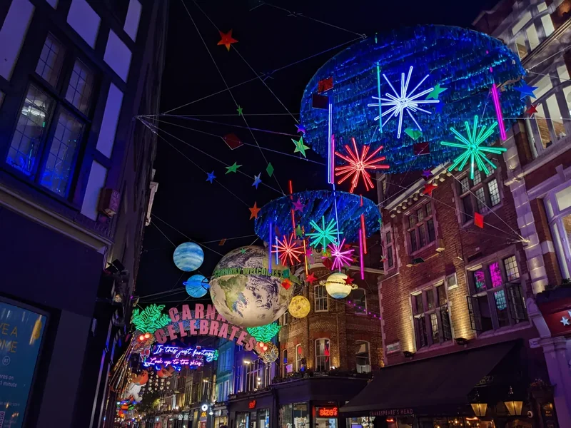 Colourful hanging Christmas decorations over Carnaby Street at night