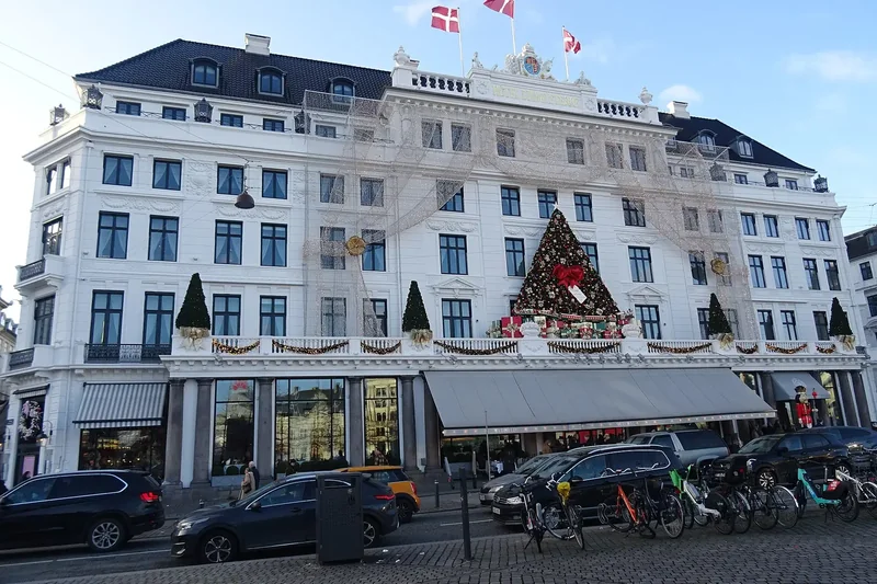 The white facade of Hotel d'Angleterre decorated with a large Christmas tree and garlands, Danish flags on the roof