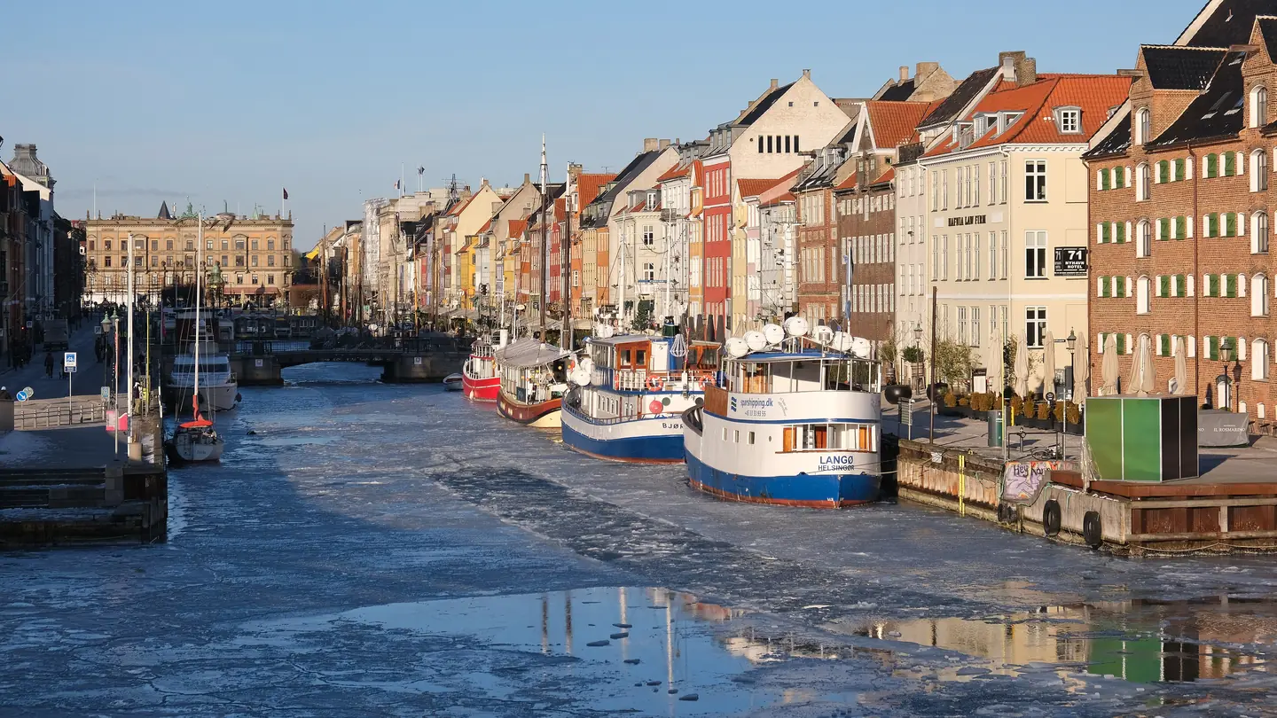 Nyhavn canal in Copenhagen with ice on the water, moored boats and coloured gabled houses