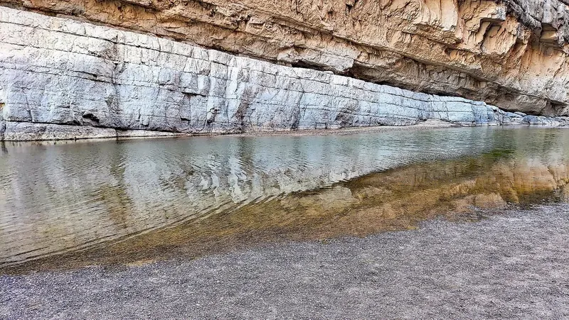 Still water of the Rio Grande reflecting a sheer limestone cliff inside Santa Elena Canyon