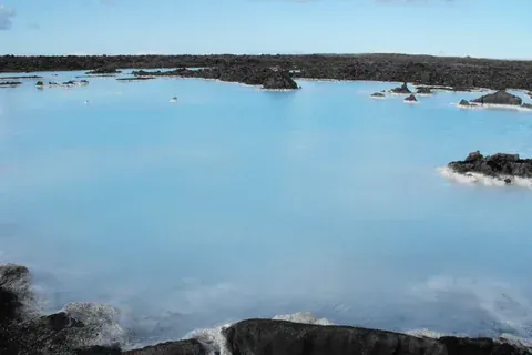The milky-blue geothermal water of the Blue Lagoon among dark lava rocks