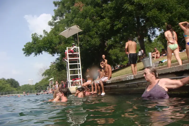 A swimmer jumping from the diving board at Barton Springs Pool