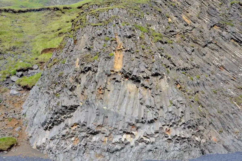 Columnar basalt rising in grey hexagonal columns at Reynisfjara