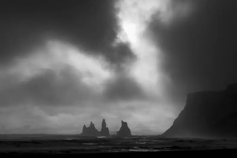 Black-and-white view of the Reynisdrangar sea stacks under storm clouds near Vík