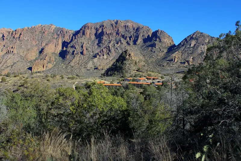 The Chisos Mountains Lodge cabins tucked against steep rocky peaks under a clear blue sky
