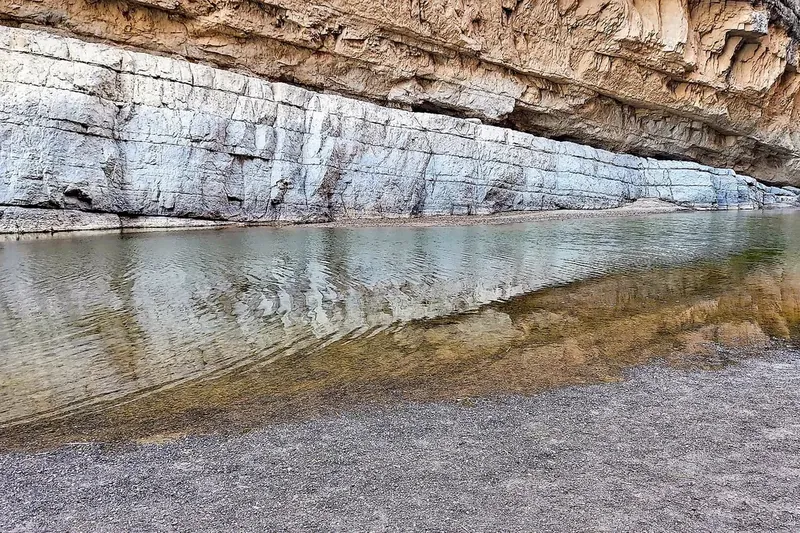 Still water of the Rio Grande reflecting a sheer limestone cliff inside Santa Elena Canyon