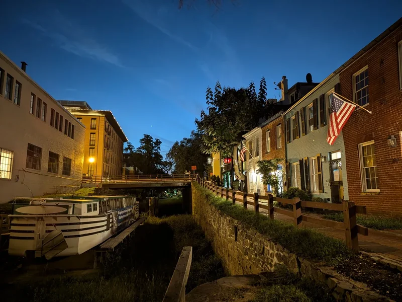 The C&O Canal in Georgetown at dusk, with brick buildings and lights reflected in the water