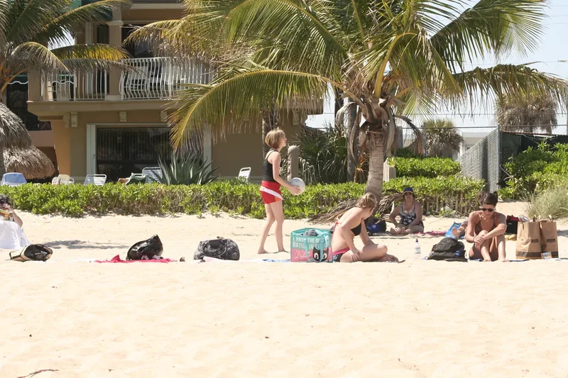 People relaxing on the sand at Lauderdale-By-The-Sea under palms