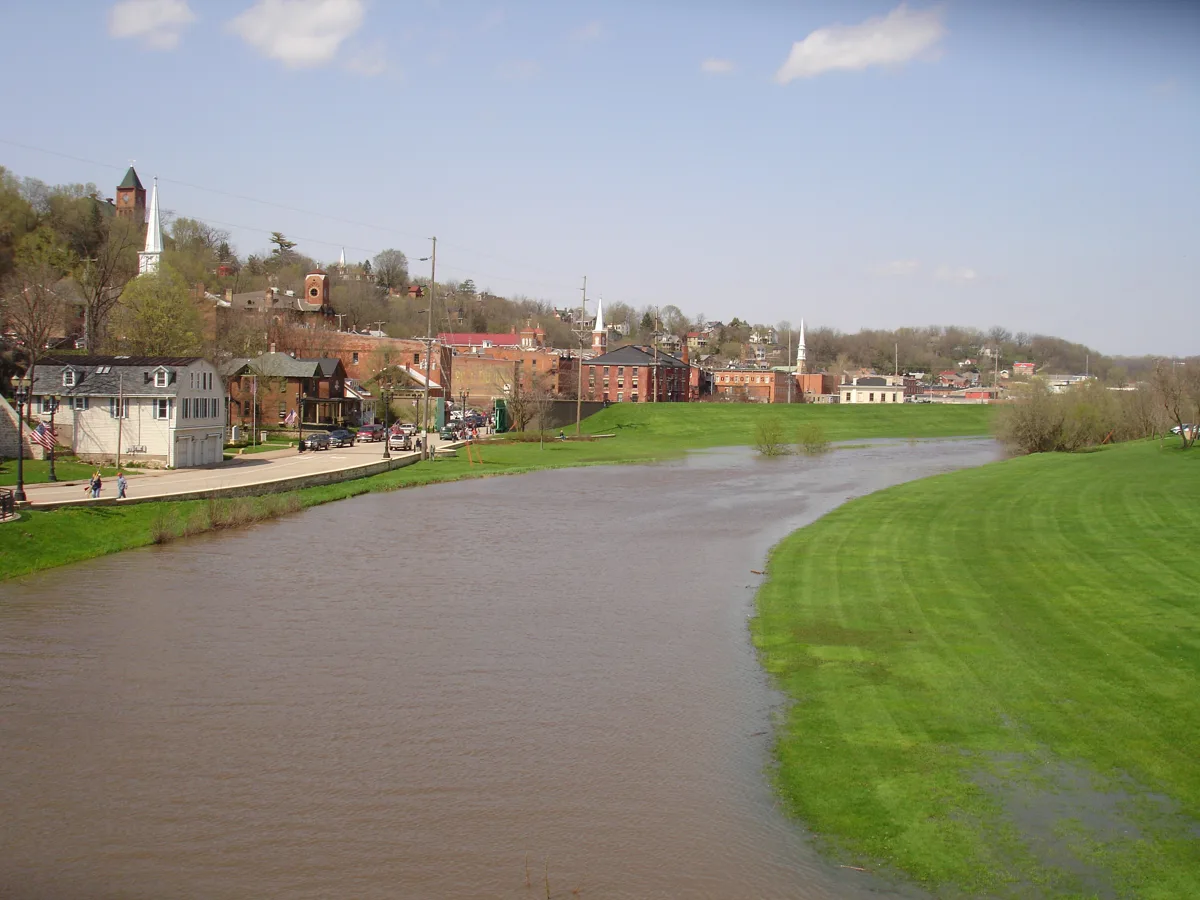 The Galena River running past grassy levee banks, with brick buildings of downtown Galena beyond