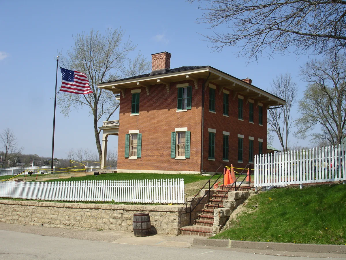 The Ulysses S. Grant Home, a red-brick Italianate house with a porch, a flagpole and a white fence