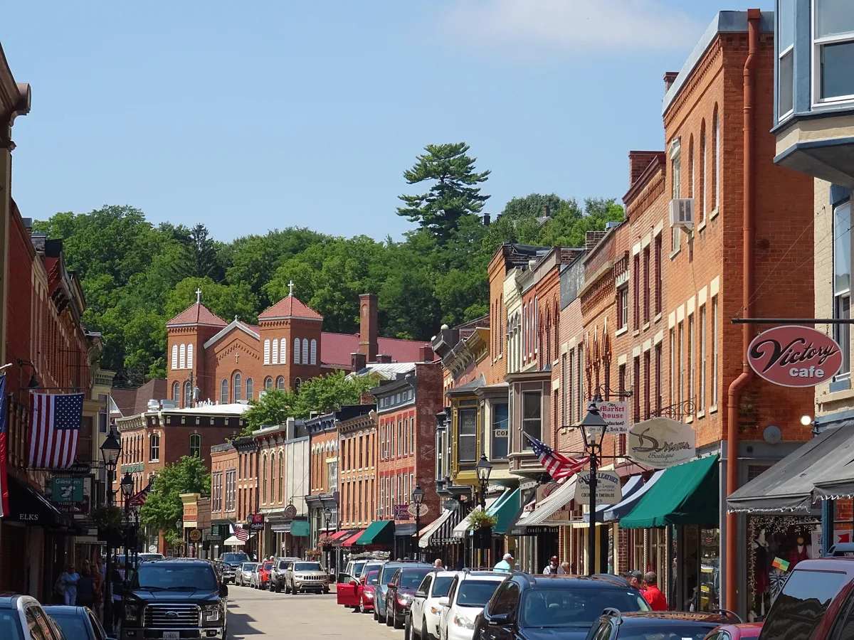 Galena’s Main Street curving between two- and three-story brick buildings with awnings, wooded hills behind
