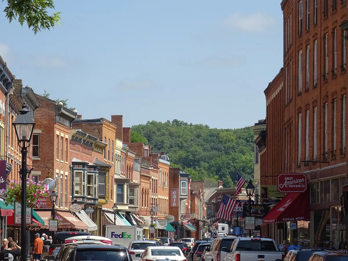 A steep view down Main Street in Galena with brick buildings, flags and wooded hills