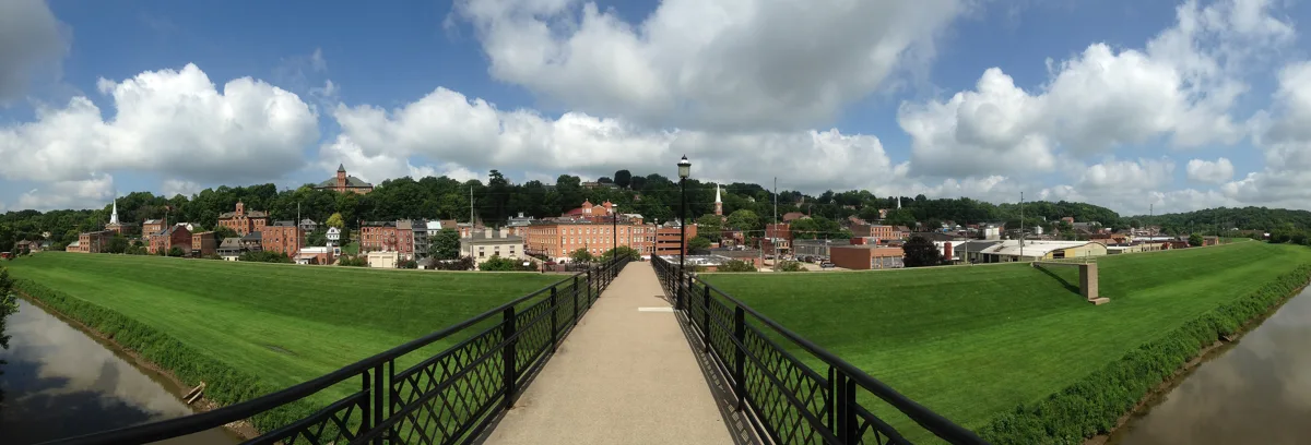 A wide view of downtown Galena from the footbridge over the river, brick buildings and steeples on the hillside