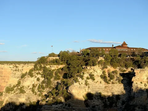 El Tovar Hotel’s dark timber lodge on the rim above a sunlit canyon wall