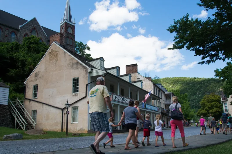 Visitors walking along a Lower Town street in Harpers Ferry past stone and brick buildings