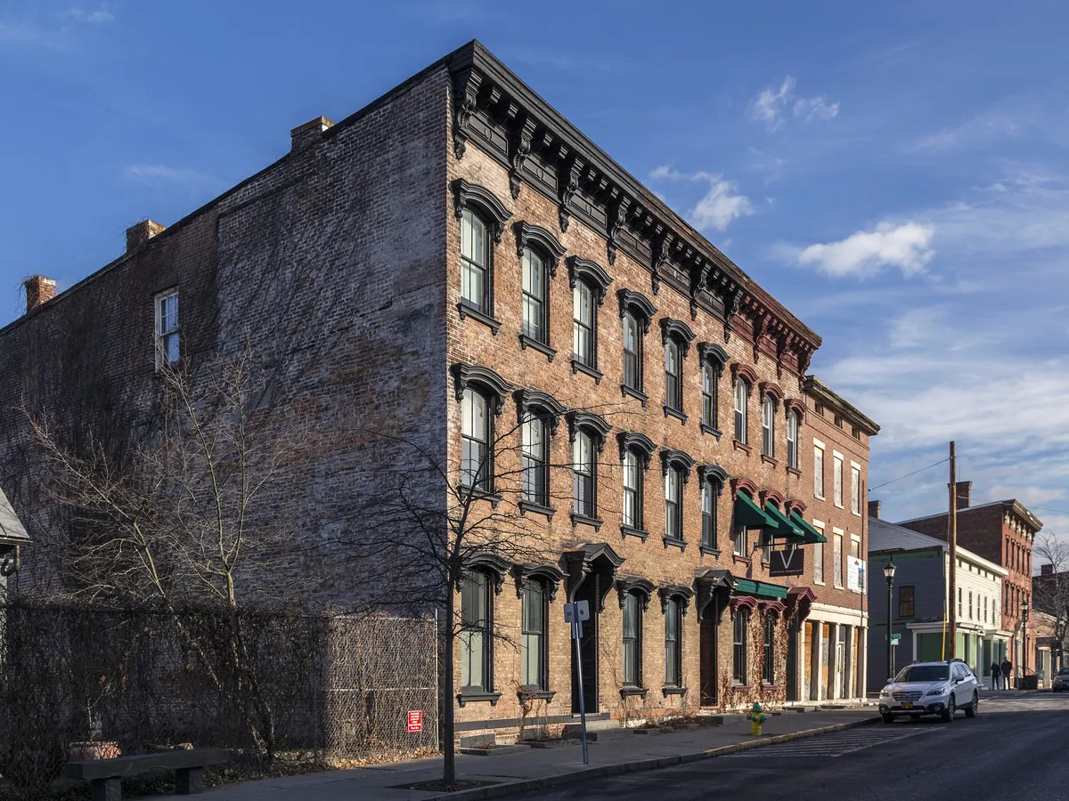 Warren Street in Hudson looking east, with 19th-century brick and stone buildings along the main street under a blue sky